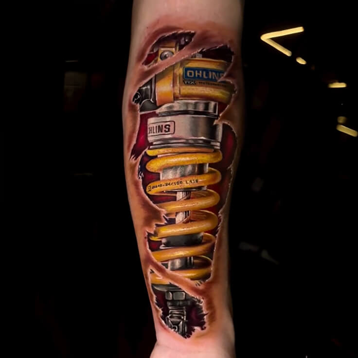 This stunning biomechanical tattoo by Soumen Dutta gives the illusion of torn skin revealing a highly realistic Öhlins motorcycle suspension spring underneath.
