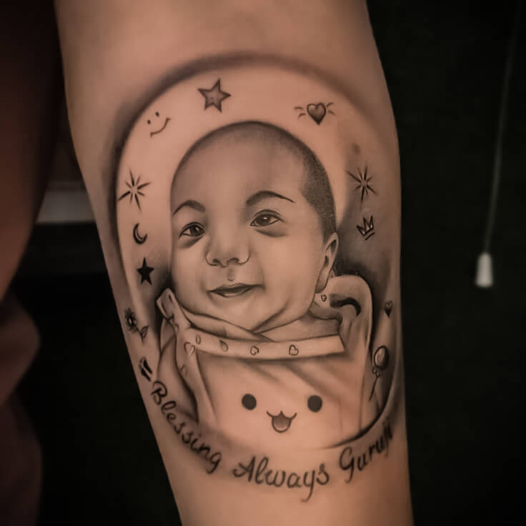 Smiling baby with spiritual symbols tattoo by Sohil Khan