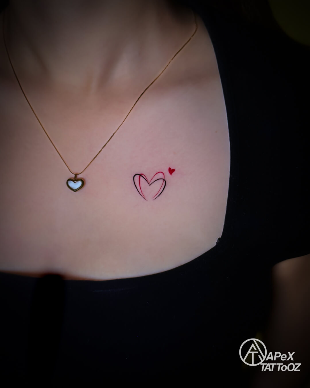 Small red and black double-heart fine line back tattoo by Apex Tattooz