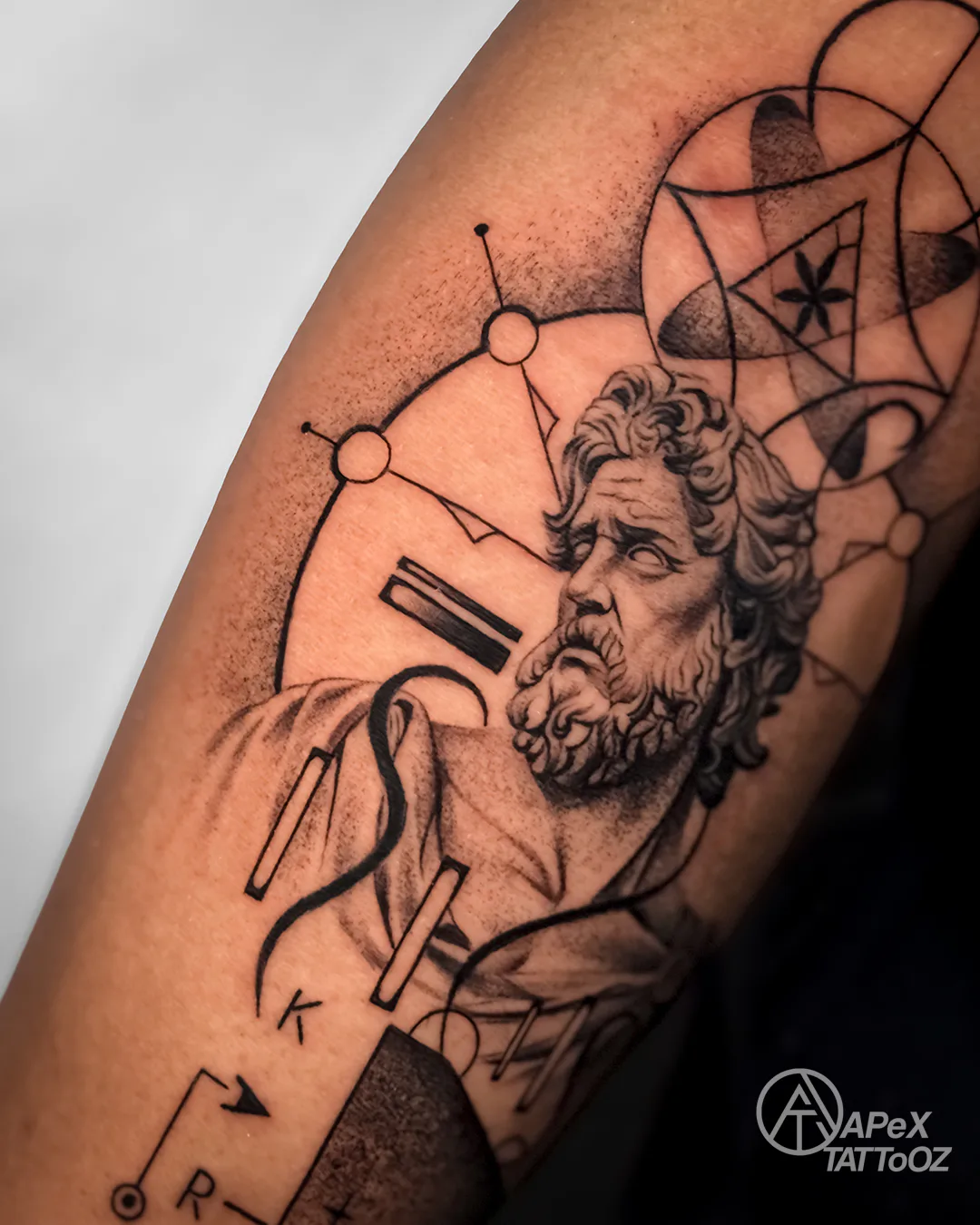 Close view of a classical Greek bust in a black and grey forearm tattoo