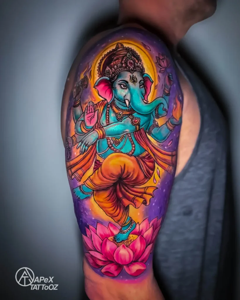 Colour Ganesha upper-arm tattoo with vivid blue, orange and pink tones by Apex Tattooz