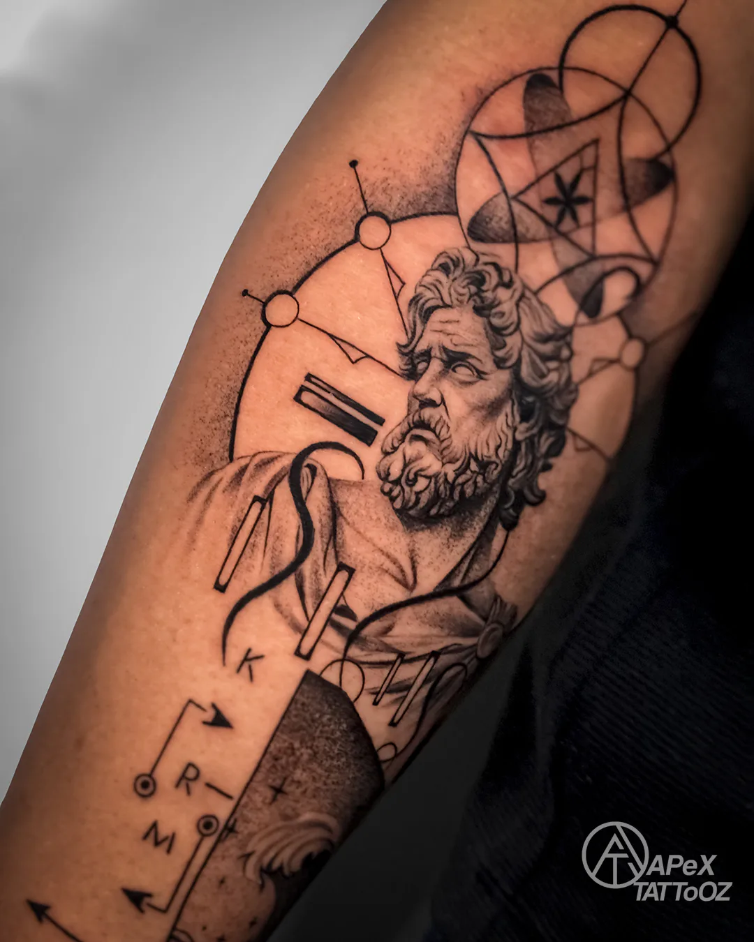 Sacred geometry and classical portrait details in a Greek-inspired tattoo