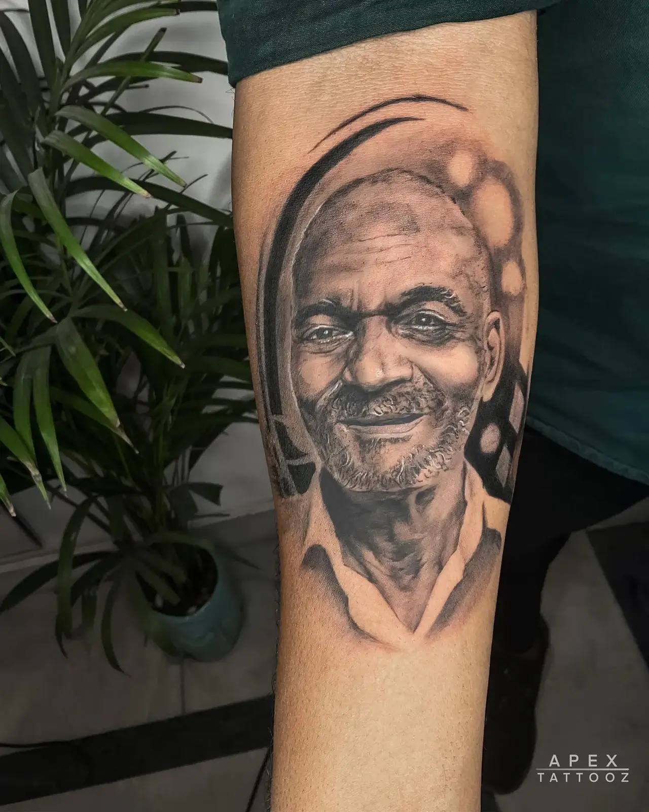 A smiling man rendered in black and grey on the forearm.